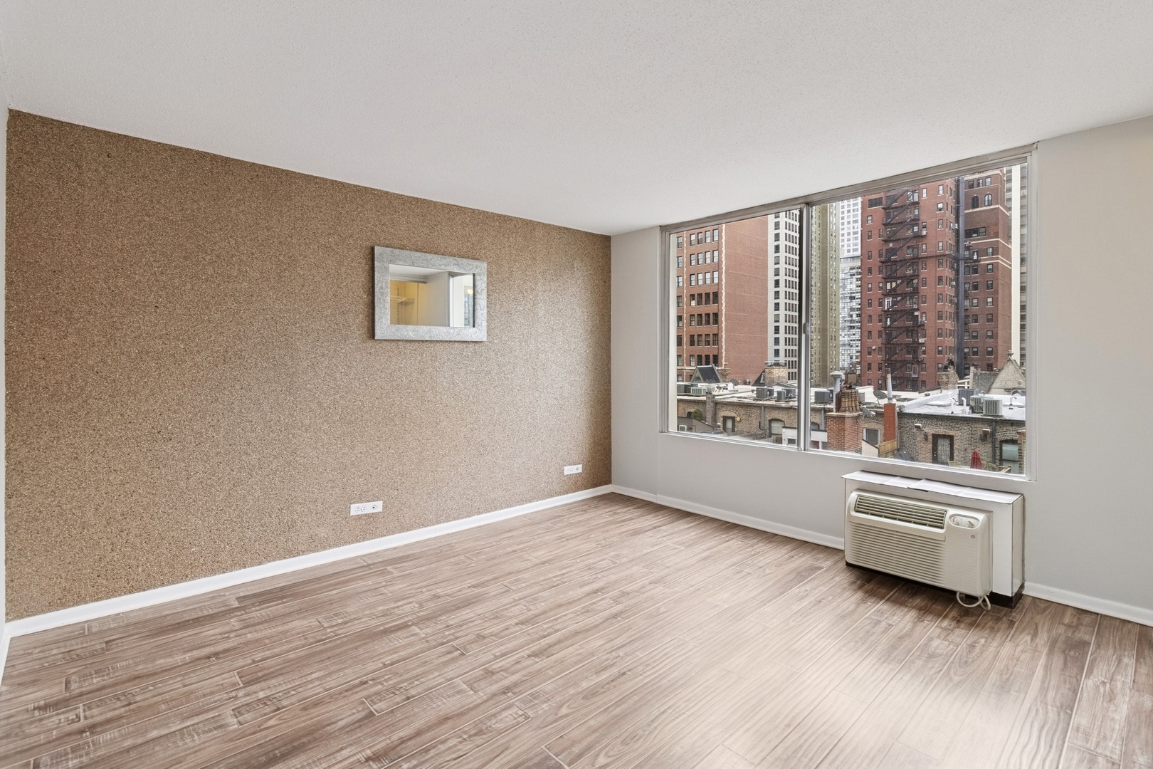 71 East Division Street, Unit 702 Chicago, IL 60611 - Photo 9 of 18 a view of an empty room with a window and wooden floor