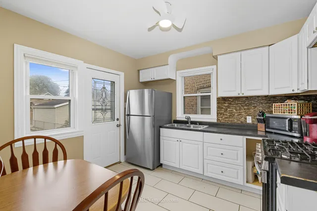 a kitchen with stainless steel appliances granite countertop a stove a refrigerator a kitchen island a sink cabinets and a dining table