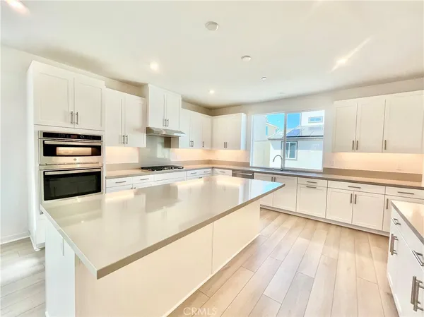 a large kitchen with stainless steel appliances granite countertop a lot of counter space and wooden floors