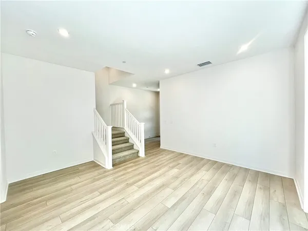 a view of an empty room with wooden floor and stairs