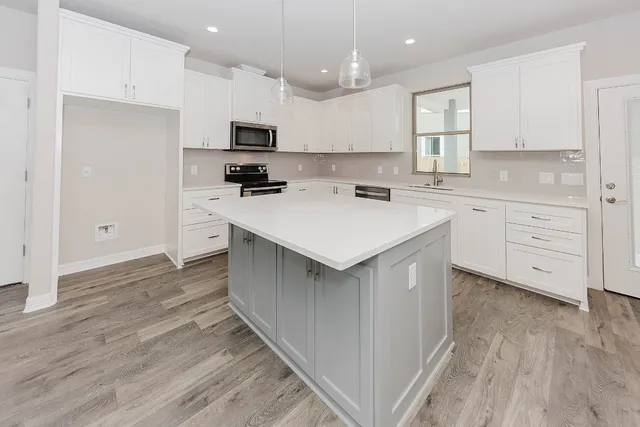 a large kitchen with kitchen island a sink a counter top space stainless steel appliances and cabinets