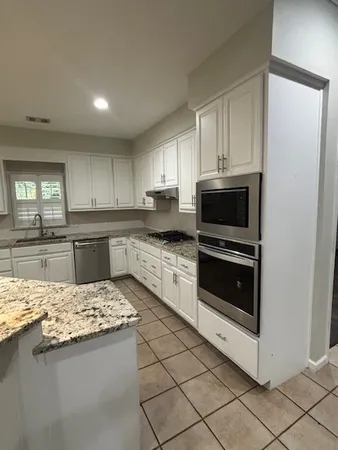 a kitchen with kitchen island granite countertop stainless steel appliances and white cabinets