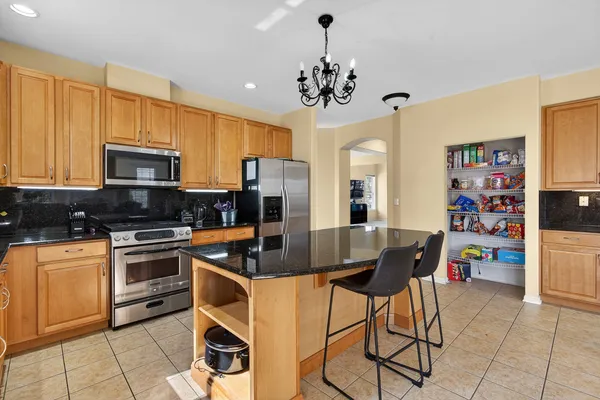 a kitchen with stainless steel appliances granite countertop a stove a refrigerator a dining table and chairs