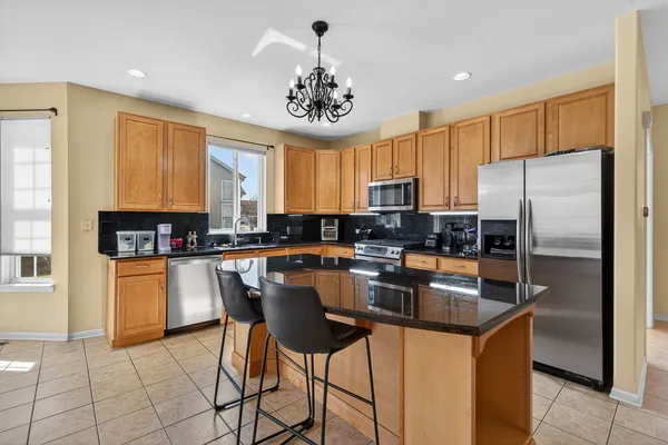 a kitchen with stainless steel appliances granite countertop a sink a stove a refrigerator cabinets and a dining table