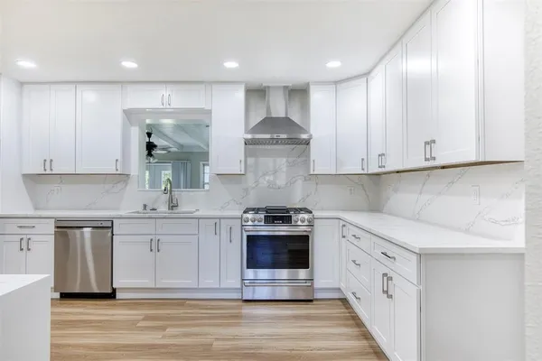 a kitchen with stainless steel appliances granite countertop a stove and white cabinets