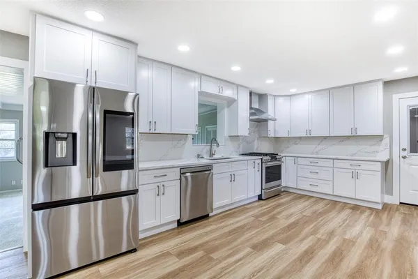 a kitchen with stainless steel appliances granite countertop a refrigerator sink and white cabinets