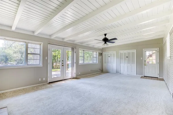 an empty room with windows and chandelier fan