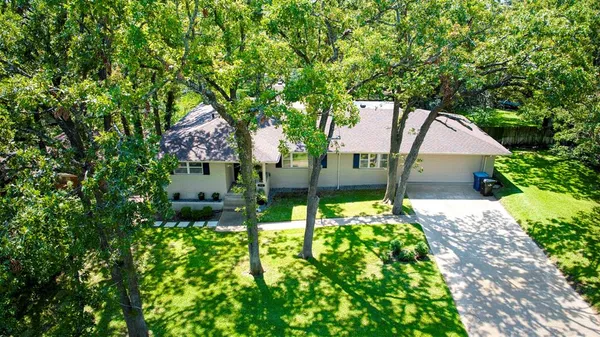 a backyard of a house with table and chairs and a large tree