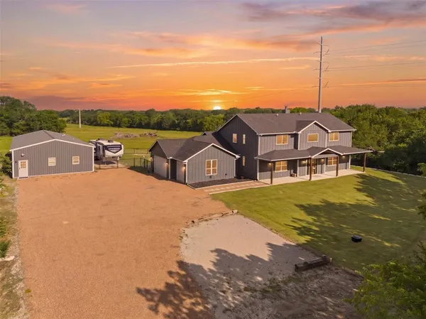 a view of a big house with a big yard and large trees