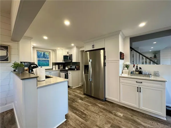 a kitchen with kitchen island a refrigerator a stove a sink cabinets and a dining table with wooden floor