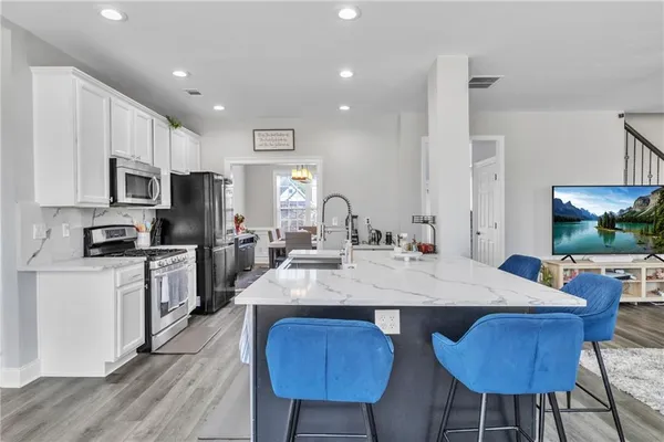a kitchen with stainless steel appliances a refrigerator a stove and white cabinets