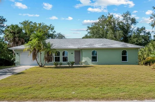a front view of house with yard and trees in the background