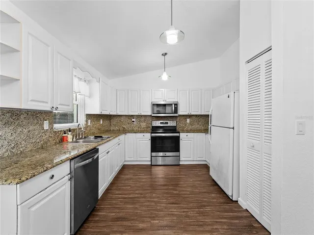 a large kitchen with cabinets wooden floor and stainless steel appliances