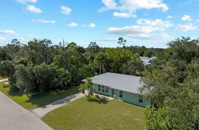an aerial view of residential houses with outdoor space and trees
