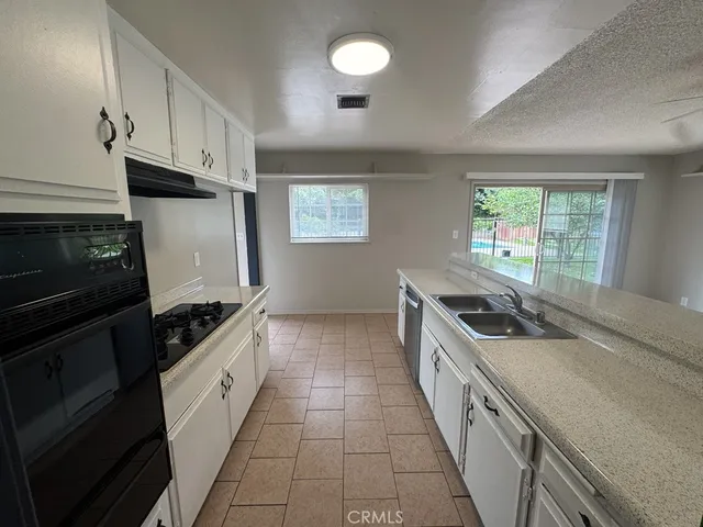 a kitchen with granite countertop a stove sink and cabinets