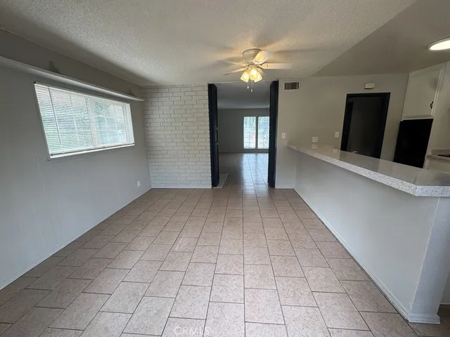 a view of an empty room with window and chandelier fan