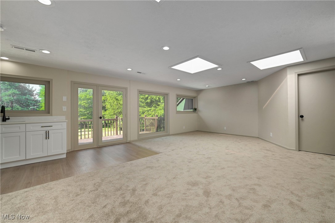 433 Chestnut Road Independence, OH 44131 - Photo 23 of 50 Unfurnished living room with recessed lighting, light colored carpet, light wood-style floors, and a skylight