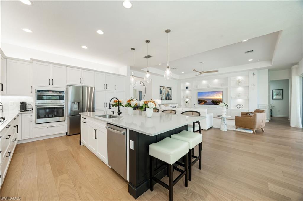 12128 Eucalyptus Way Naples, FL 34120 - Photo 11 of 47 This kitchen! Clean lines, elegant light fixtures, wood flooring, textured tile backsplash, upgraded LG refrigerator, and cabinet pull-out trays, and island seating for 6 are just a few of the features that elevate this Sunrise home.