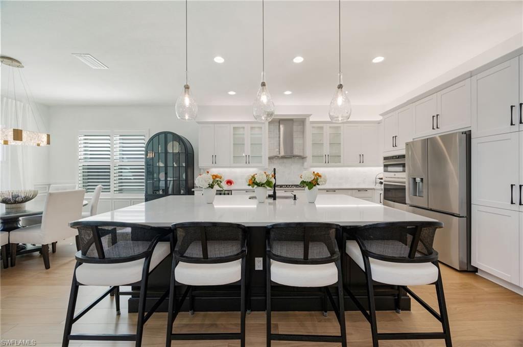 12128 Eucalyptus Way Naples, FL 34120 - Photo 13 of 47 This kitchen! Clean lines, elegant light fixtures, wood flooring, textured tile backsplash, upgraded LG refrigerator, and cabinet pull-out trays, and island seating for 6 are just a few of the features that elevate this Sunrise home.