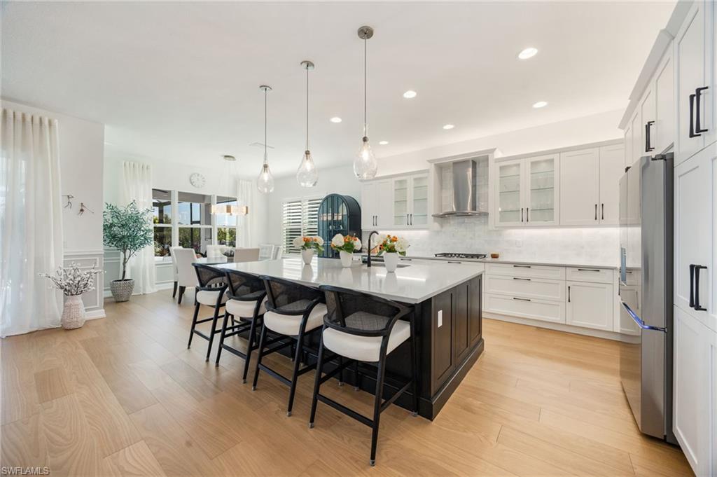 12128 Eucalyptus Way Naples, FL 34120 - Photo 14 of 47 This kitchen! Clean lines, elegant light fixtures, wood flooring, textured tile backsplash, upgraded LG refrigerator, and cabinet pull-out trays, and island seating for 6 are just a few of the features that elevate this Sunrise home.
