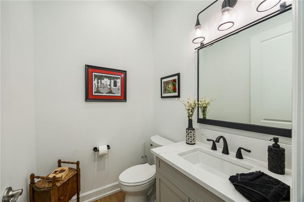 12128 Eucalyptus Way Naples, FL 34120 - Photo 16 of 47 The powder bathroom is light and bright, with wood flooring and matte black plumbing.