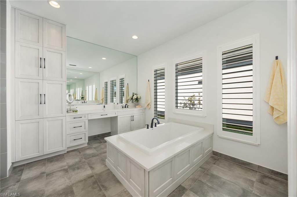 12128 Eucalyptus Way Naples, FL 34120 - Photo 18 of 47 The primary bathroom with large soaking tub, upgraded shower with frameless glass enclsoure, linen tower, and so much natural light!