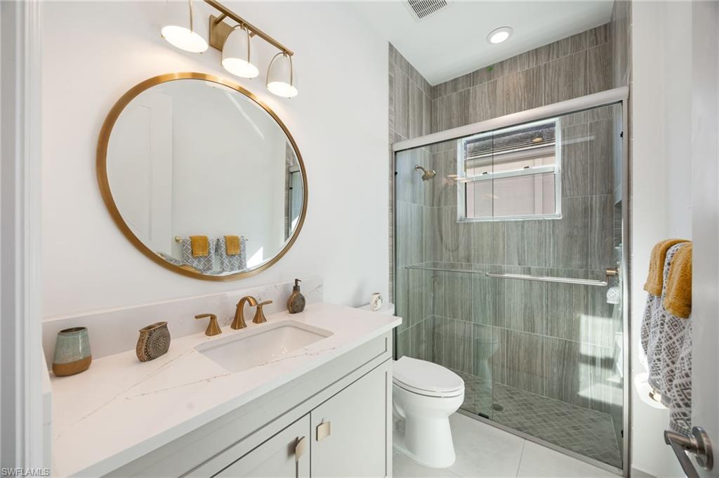 12128 Eucalyptus Way Naples, FL 34120 - Photo 21 of 47 Bathroom 2 is located within the generous bedroom 2 suite, with gold accents and a light color scheme.