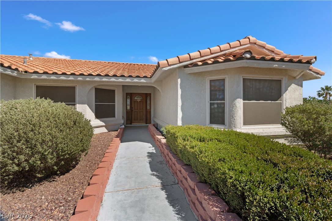 2055 Cholla Way Laughlin, NV 89029 - Photo 4 of 87 A terracotta tile roof crowns this charming home with an inviting walkway and mature landscaping.