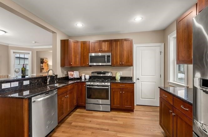 22 Myrtle Street Watertown, MA 02472 - Photo 5 of 18 a kitchen with stainless steel appliances granite countertop a stove top oven a sink dishwasher a refrigerator and a microwave oven with wooden floor