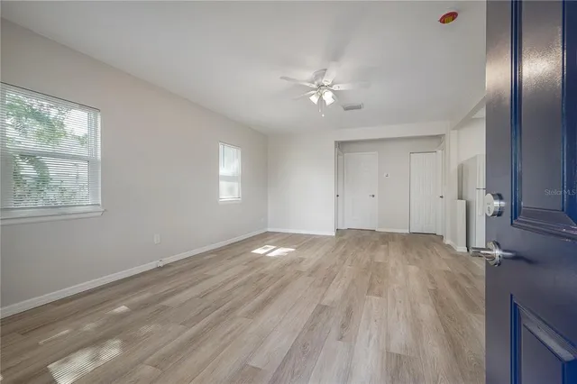 a view of empty room with wooden floor and fan