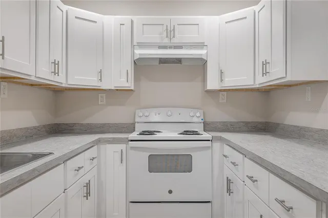 a kitchen with granite countertop white cabinets and white appliances