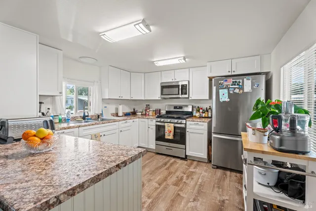 a kitchen with stainless steel appliances granite countertop a refrigerator sink stove microwave and cabinets