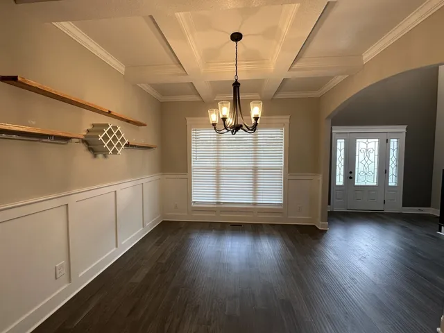 a view of a room with wooden floor chandelier and windows