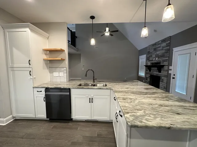 a kitchen with kitchen island granite countertop a sink cabinets and stainless steel appliances