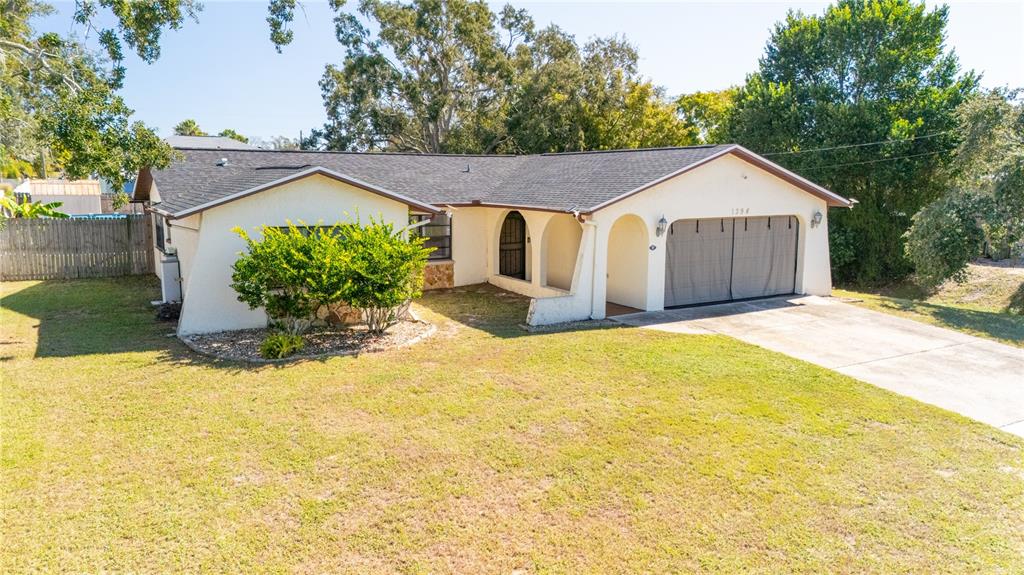 1394 Escobar Avenue Spring Hill, FL 34608 - Photo 2 of 47 a front view of house with yard and trees in the background