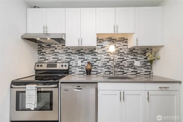 a kitchen with granite countertop a stove and a white cabinets