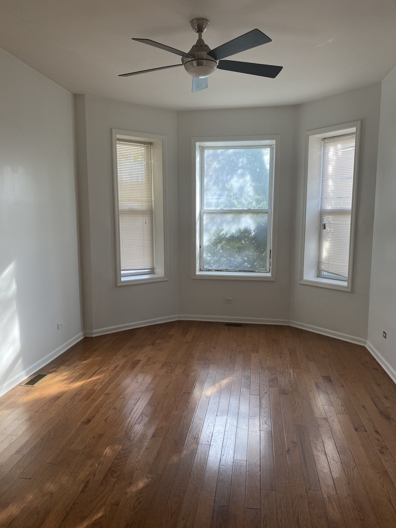 6424 South Morgan Street, Unit 1 Chicago, IL 60621 - Photo 6 of 7 an empty room with wooden floor chandelier fan and windows