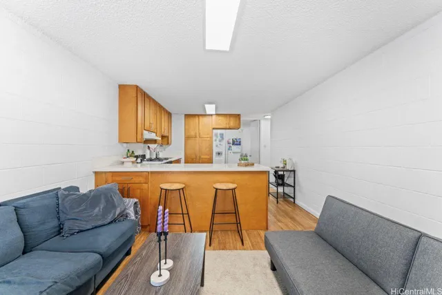 a living room with stainless steel appliances furniture a rug and a window