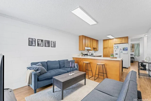 a living room with furniture a kitchen view and a refrigerator