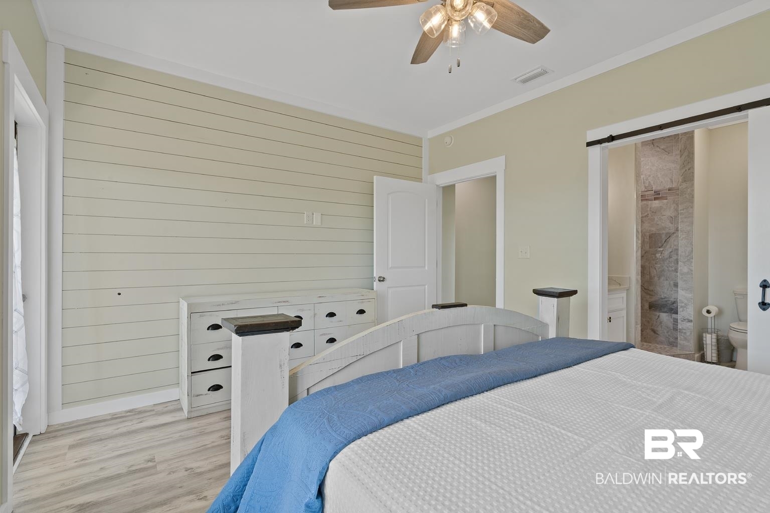 2586 Muscogee Road Gulf Shores, AL 36542 - Photo 22 of 55 Bedroom featuring ceiling fan, wood walls, ornamental molding, connected bathroom, and light hardwood / wood-style floors