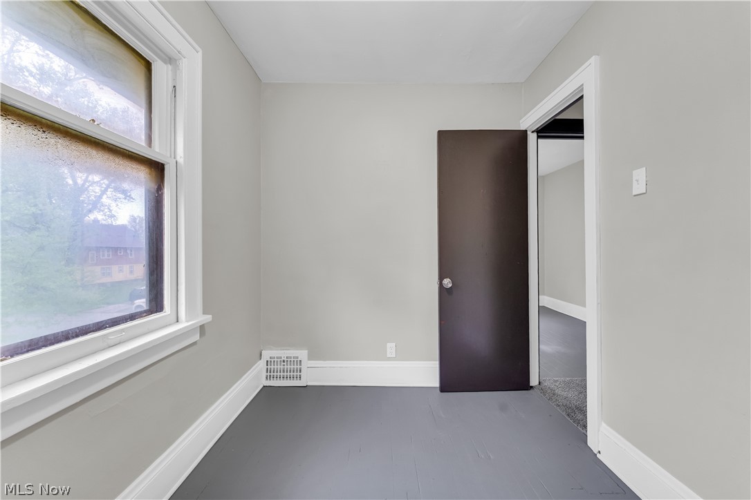 1144 East 145th Street, Unit 1/RIGHT Cleveland, OH 44110 - Photo 14 of 20 Room featuring light gray walls, dark gray flooring, white trim, a single window, and a dark brown door with a brushed nickel knob
