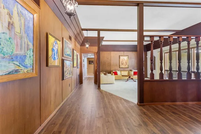 a spacious bedroom with a bed a mirror on dresser and a chandelier