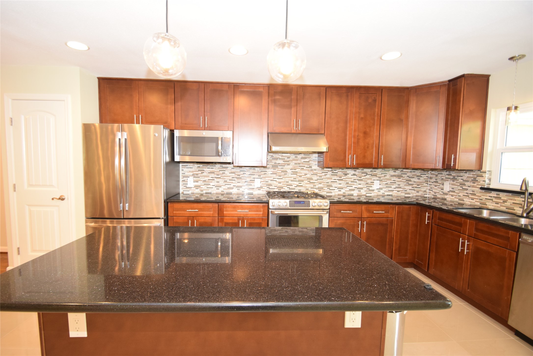 8434 Bluegate Street Houston, TX 77025 - Photo 11 of 28 a kitchen with stainless steel appliances granite countertop a refrigerator a stove and a sink with wooden cabinets