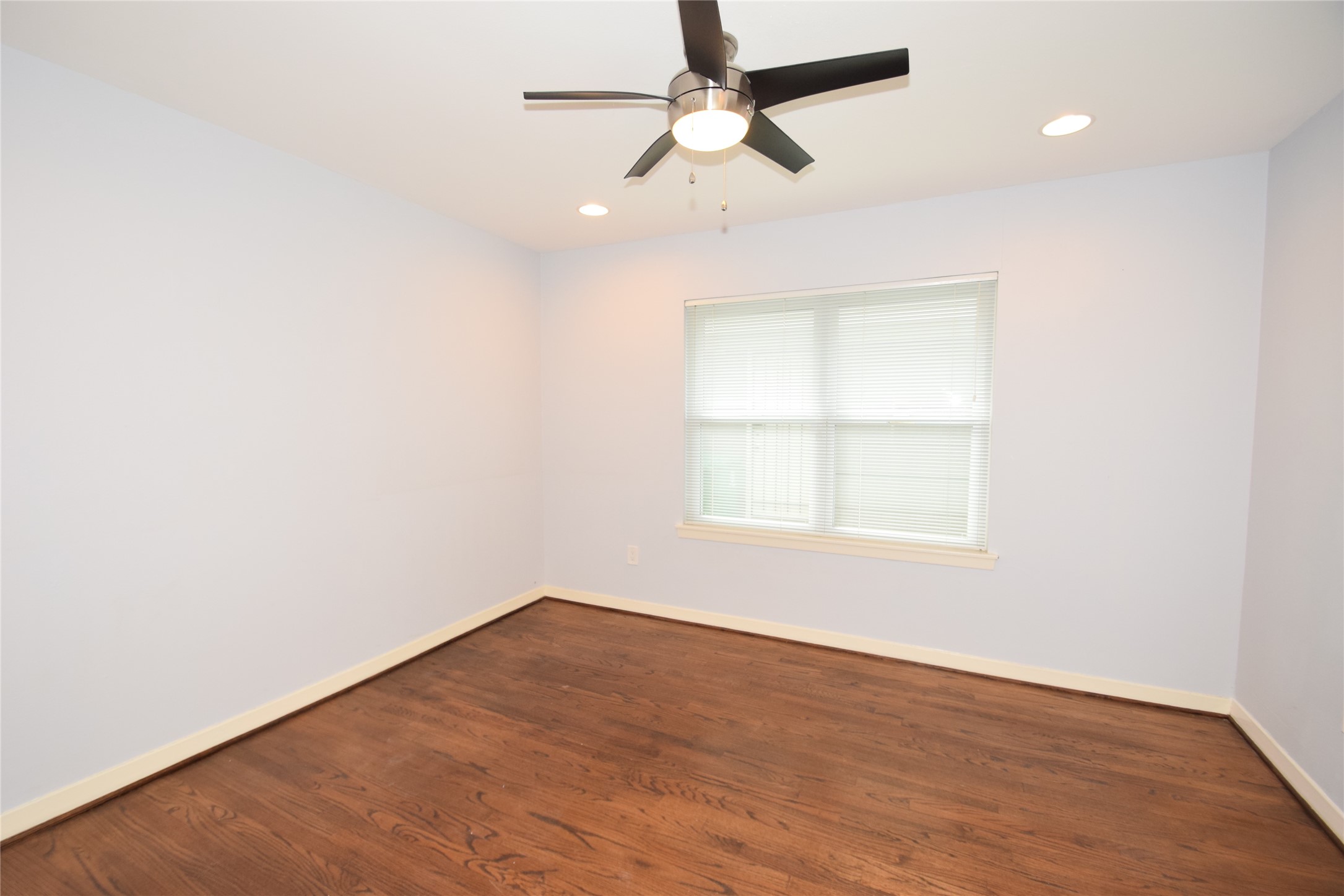8434 Bluegate Street Houston, TX 77025 - Photo 22 of 28 an empty room with wooden floor ceiling fan and window