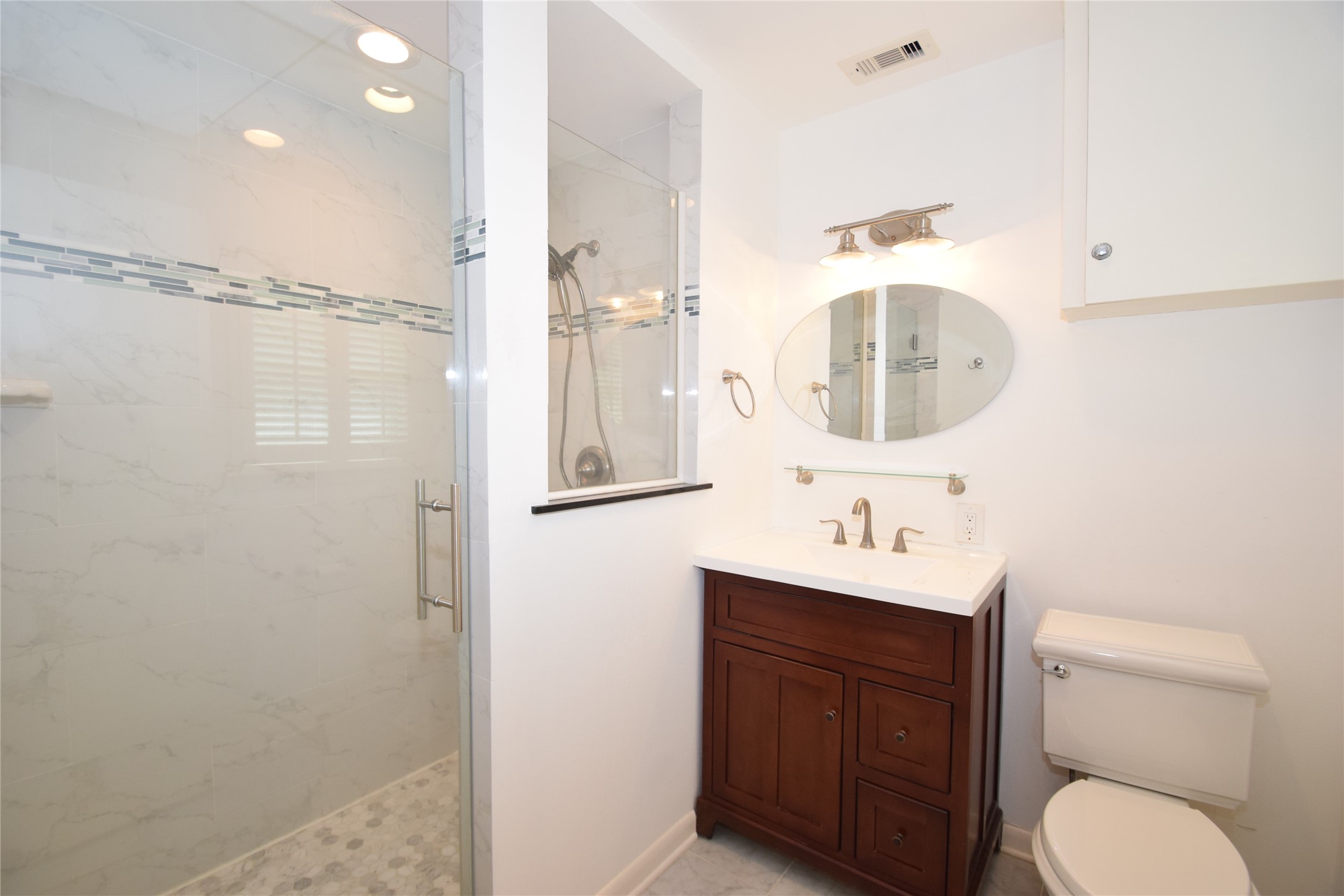 8434 Bluegate Street Houston, TX 77025 - Photo 28 of 28 a bathroom with a toilet a sink a mirror a vanity and shower