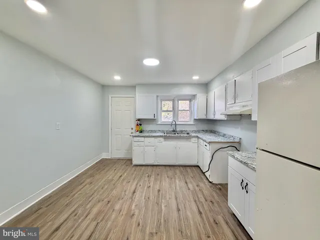 a large white kitchen with wooden floor