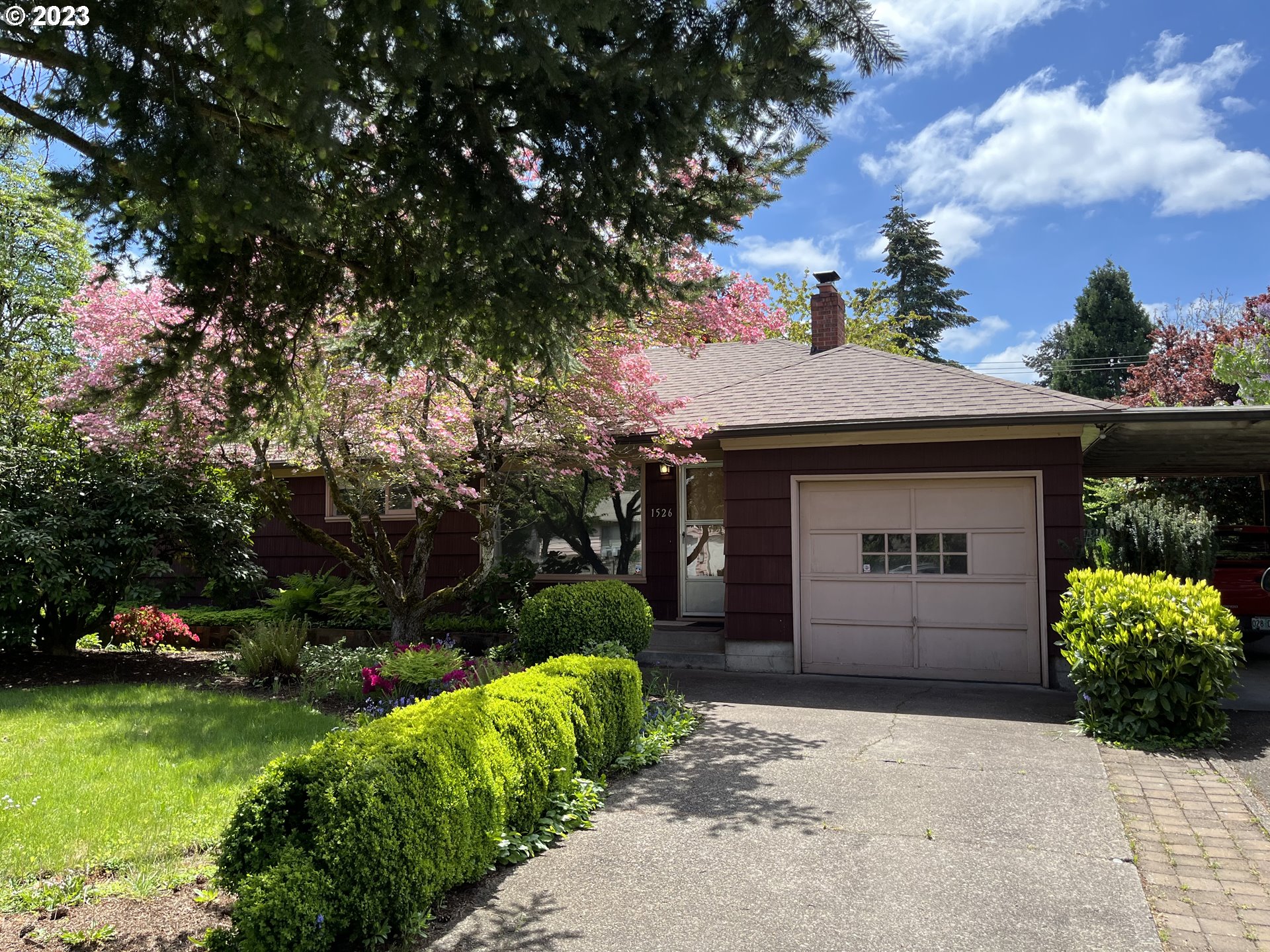 a front view of a house with a garden and trees