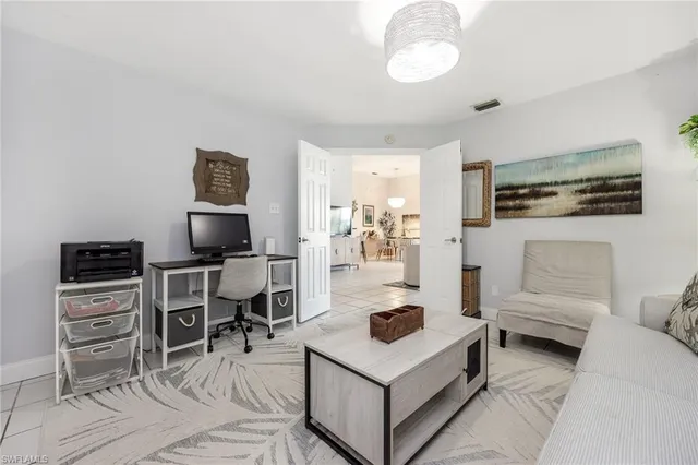 a living room with furniture a flat screen tv and kitchen view
