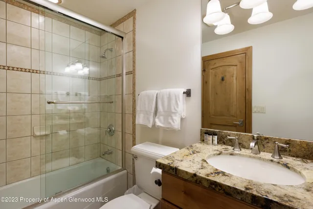 a bathroom with a granite countertop sink a toilet and shower