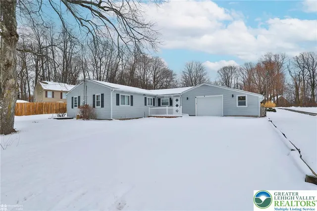 a front view of a house with a garden and trees